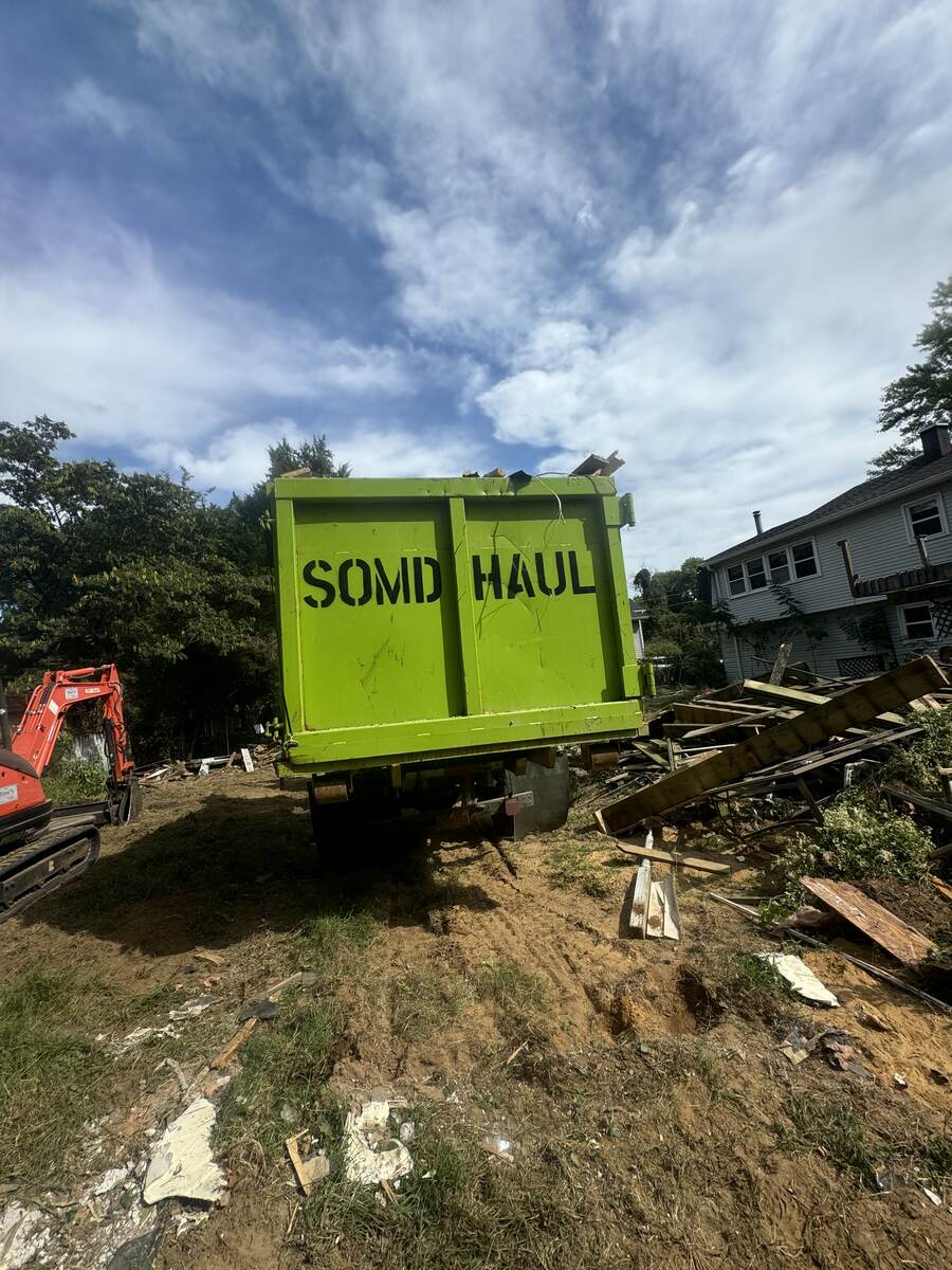 SOMD Hauling roll-off dumpster on a demolition site in Southern Maryland