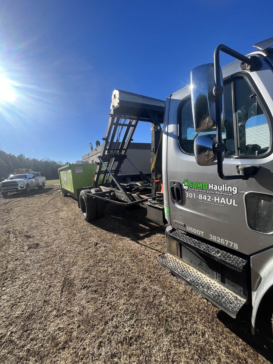 SOMD Hauling roll-off dumpster truck with company branding and USDOT number