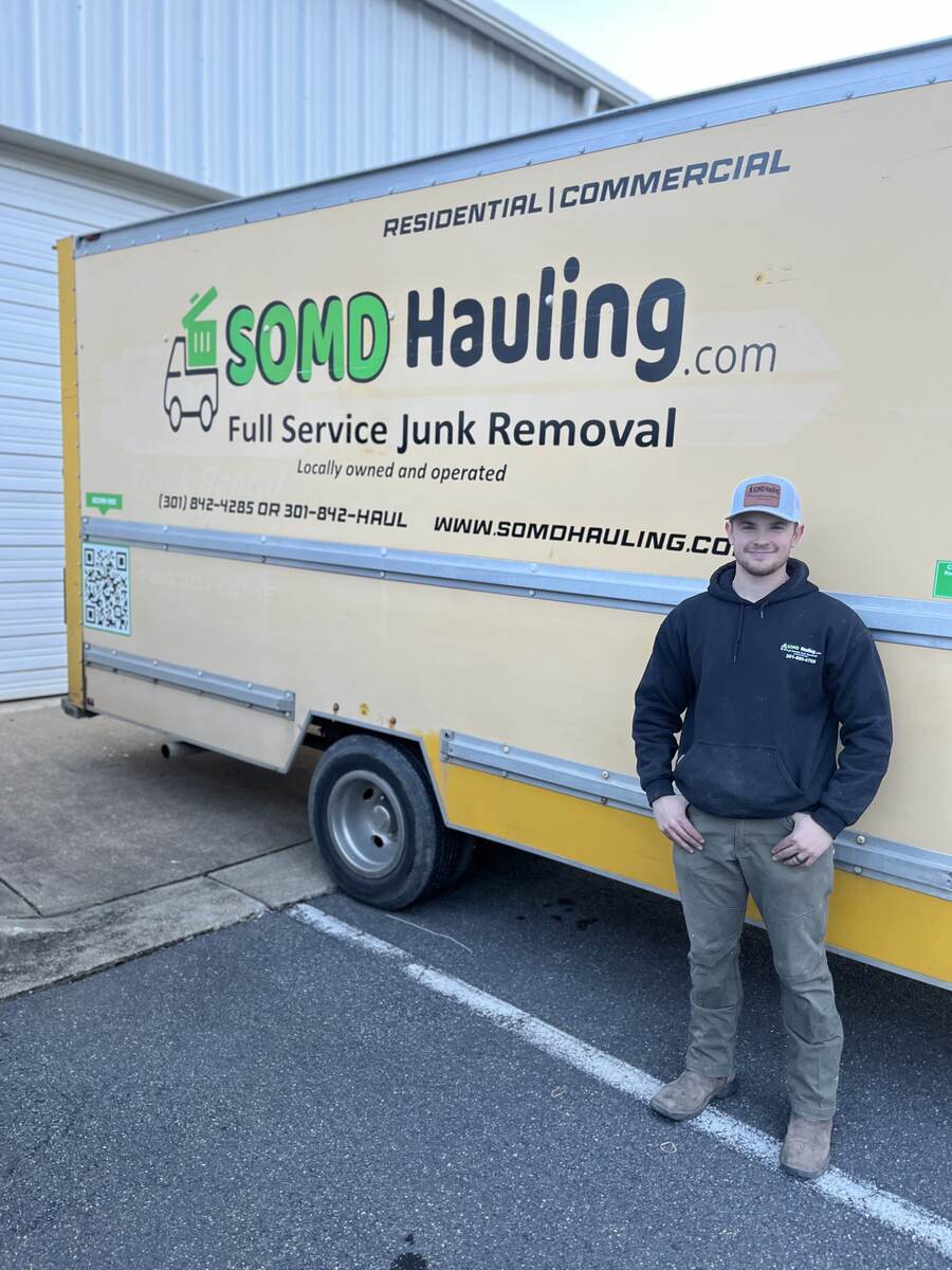 SOMD Hauling team member standing next to a branded junk removal trailer